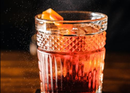 Bartender expressing an orange peel over a cocktail